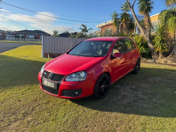Red Volkswagen Golf GTI parked on grass